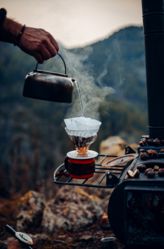 Picture of coffee being made with the pour-over method on a camp stove in the mountains