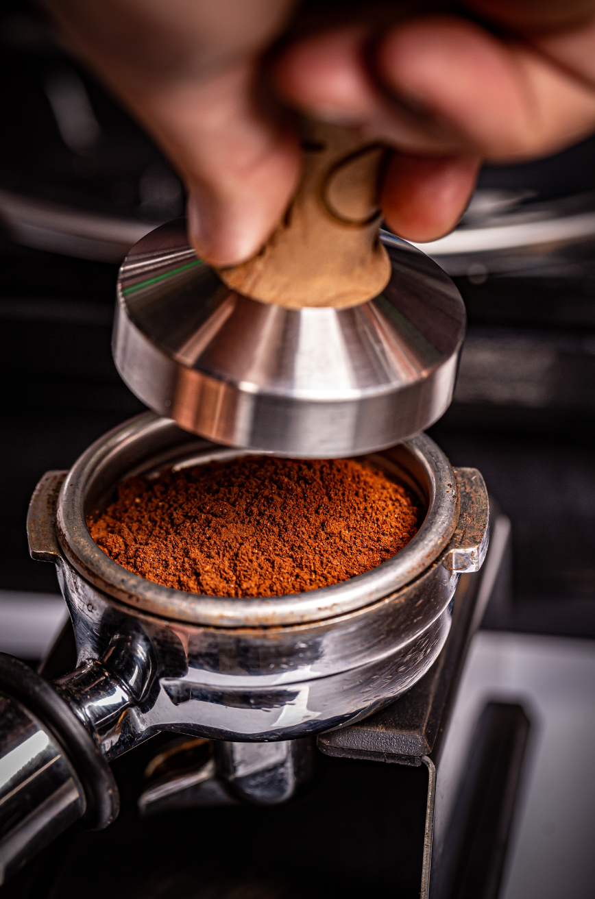 Picture of someone about to press coffee into an espresso machine Portafilter