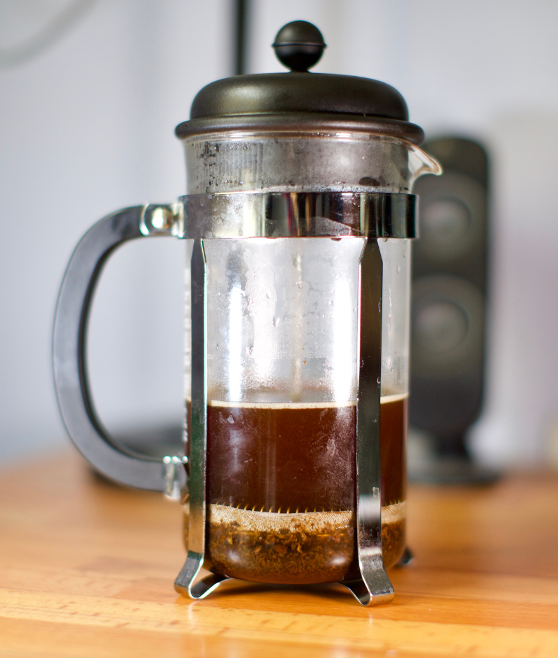 Picture of a french press half filled with fresh pressed coffee
